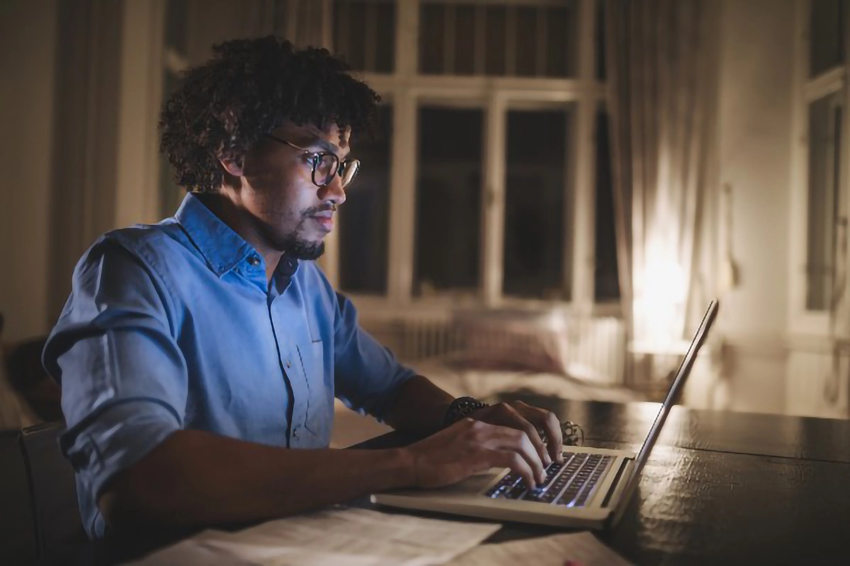 a man using a laptop in a low lit room